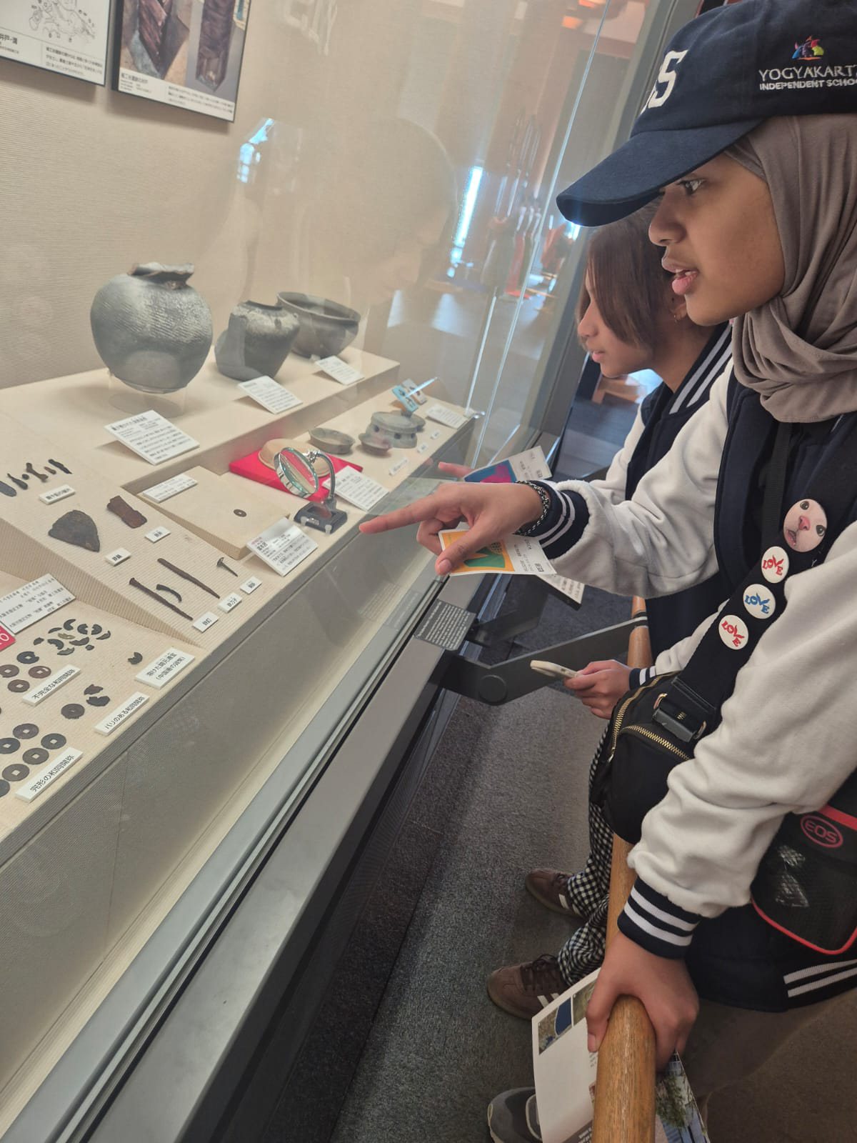 YIS student looking closely at museum artifacts in a display case